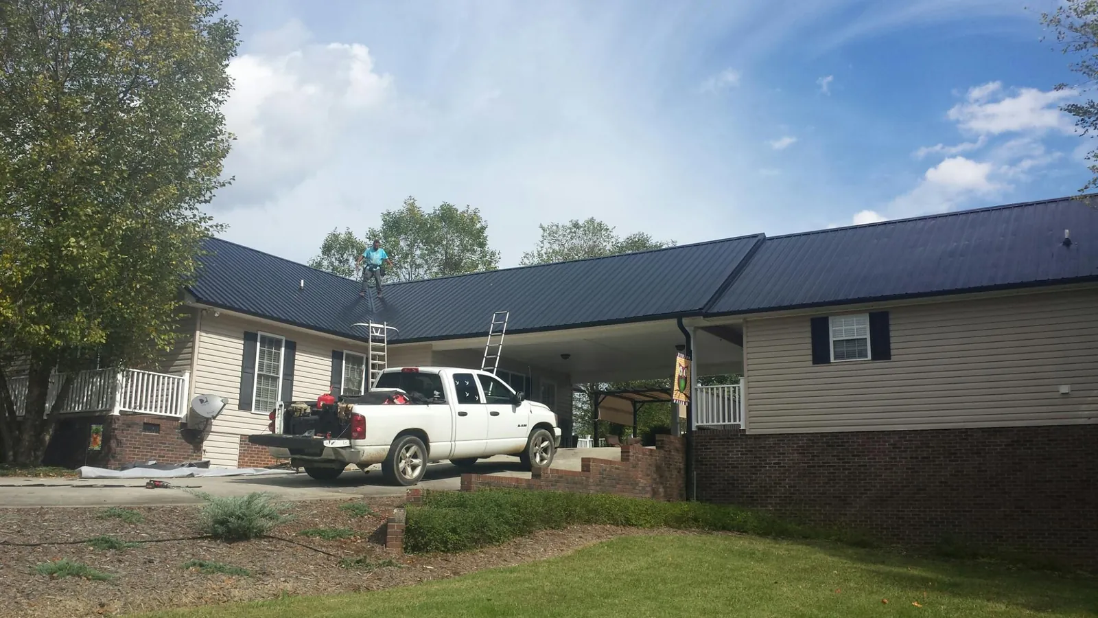 Black metal roof over a home and attached breezeway with ladders set in Warsaw